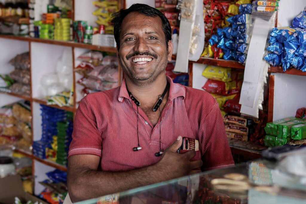 Smiling Indian shop owner behind his store counter